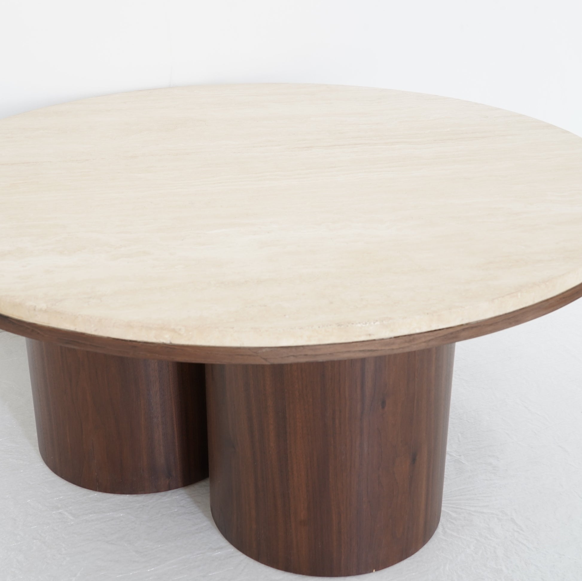 Round travertine coffee table with wooden legs, inspired by desert contours, styled in a contemporary living room.