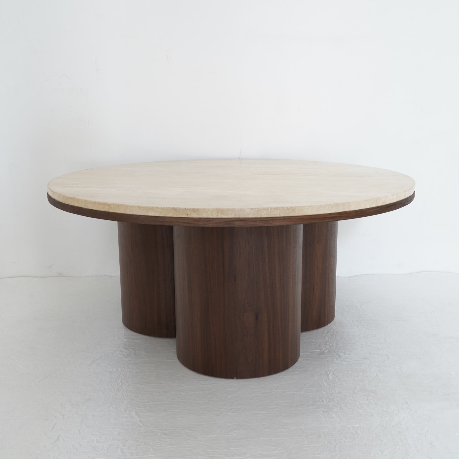 Round travertine coffee table with wooden legs, inspired by desert contours, styled in a contemporary living room.