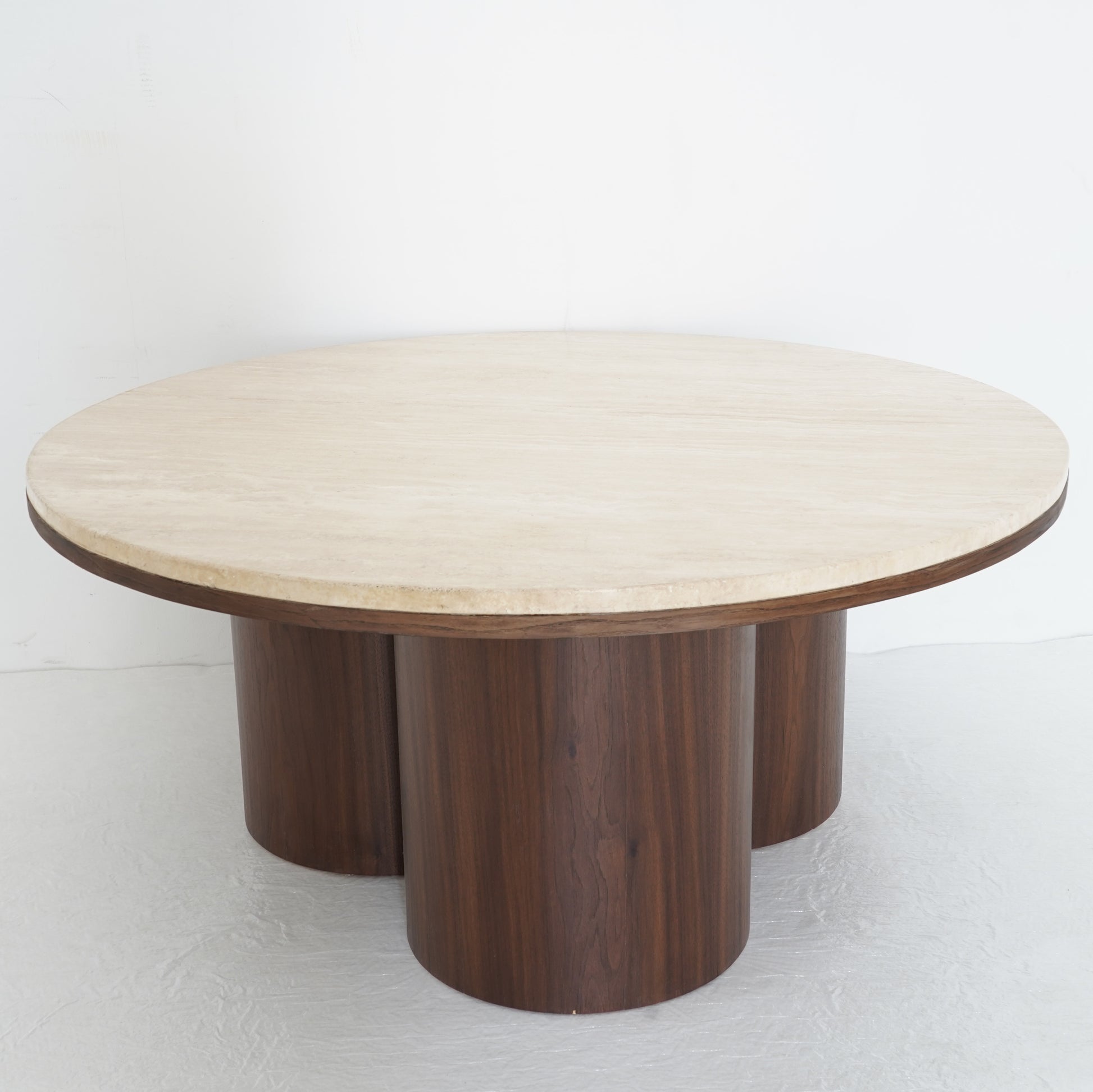 Round travertine coffee table with wooden legs, inspired by desert contours, styled in a contemporary living room.