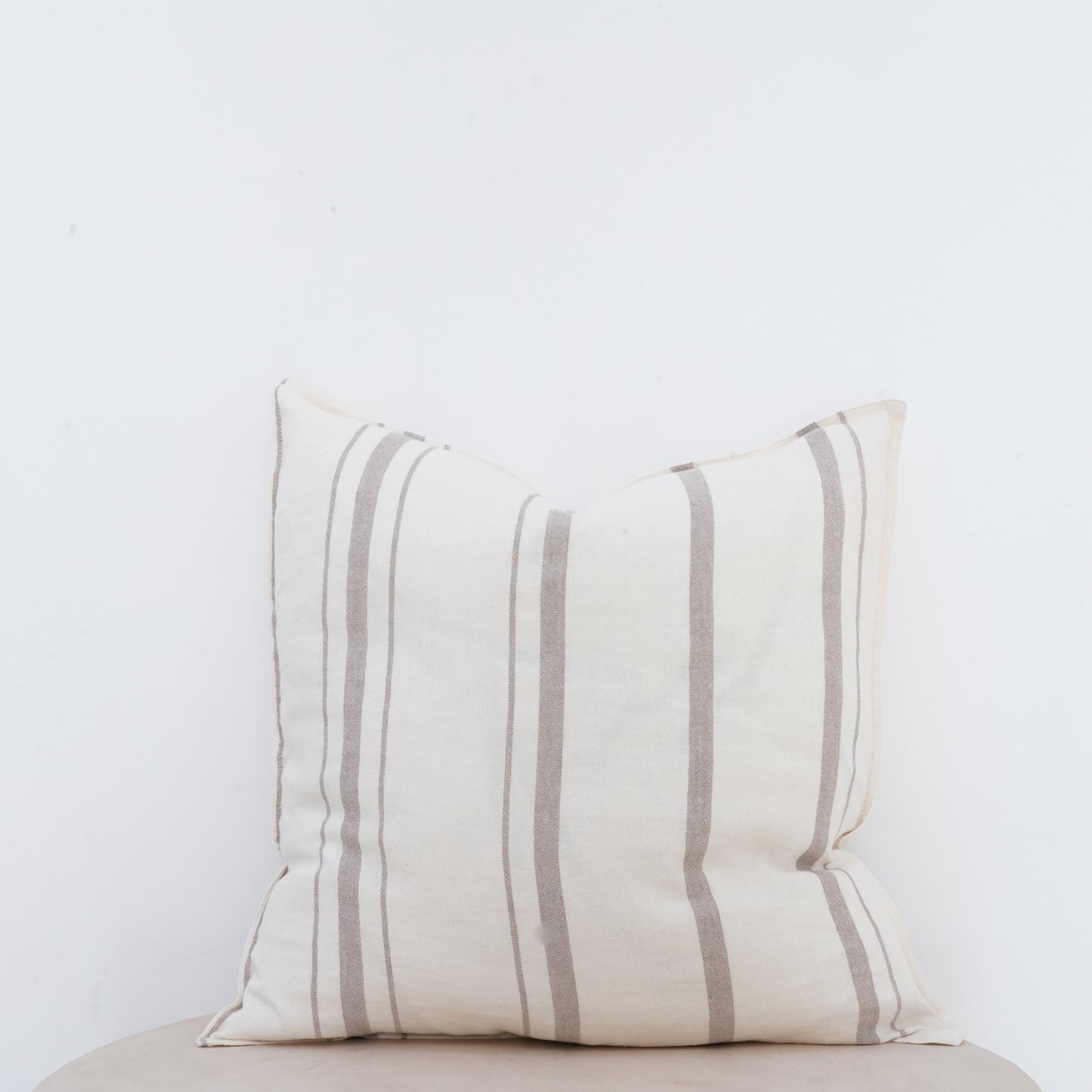 Fawn linen cushion with soft texture and French seam detailing.