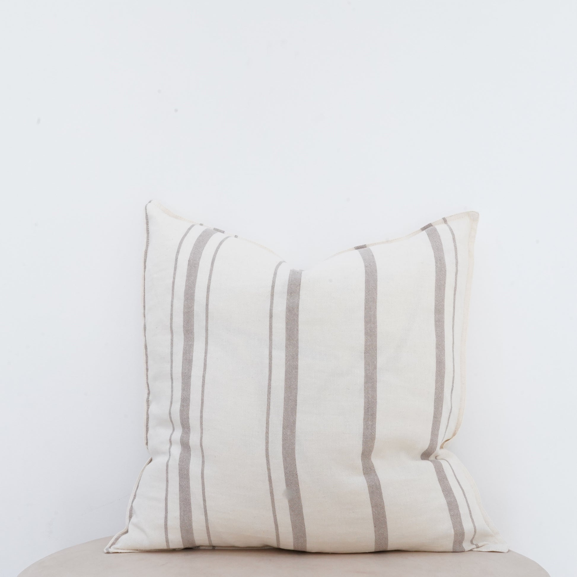 Fawn linen cushion with soft texture and French seam detailing.