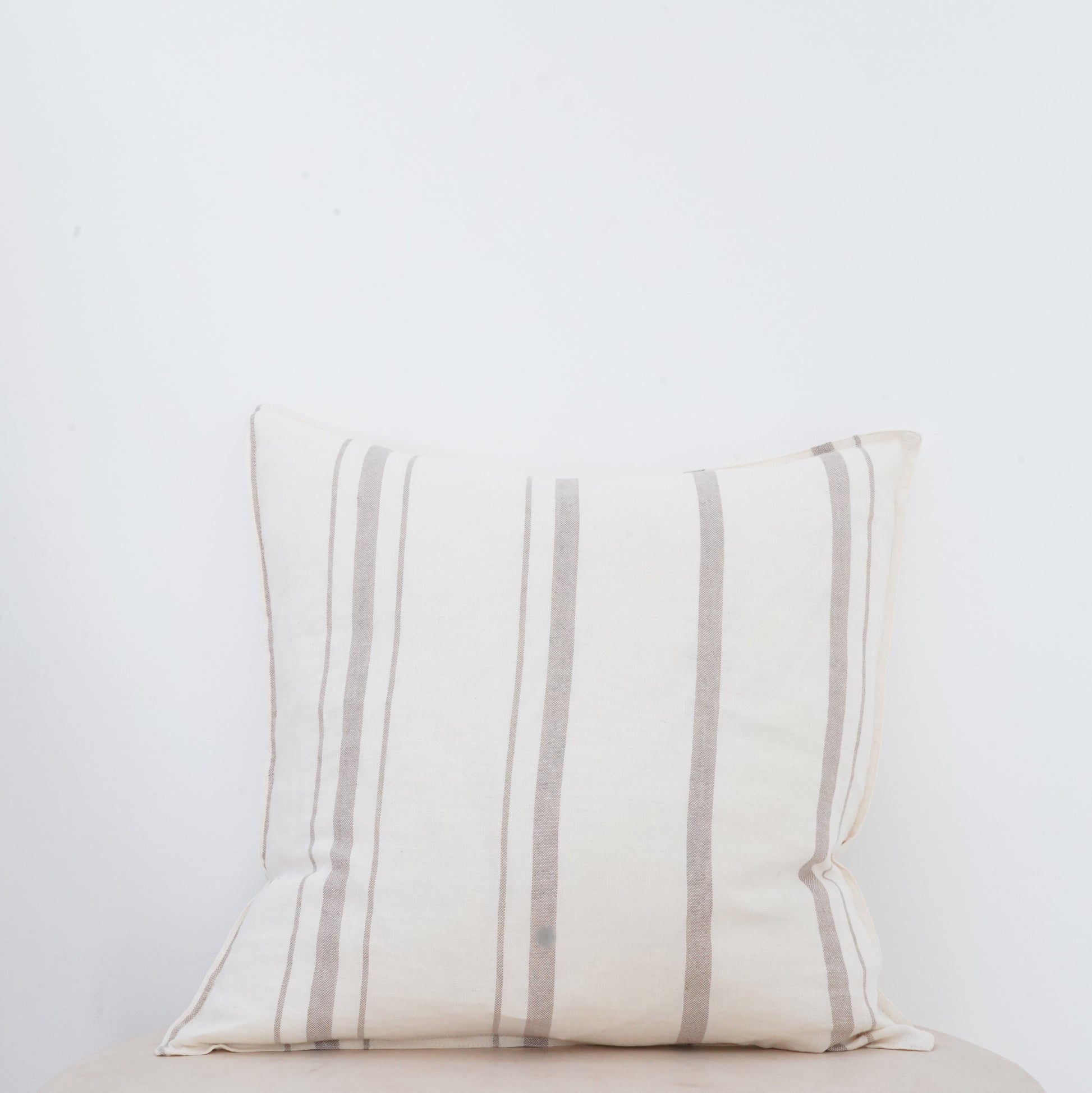 Fawn linen cushion with soft texture and French seam detailing.
