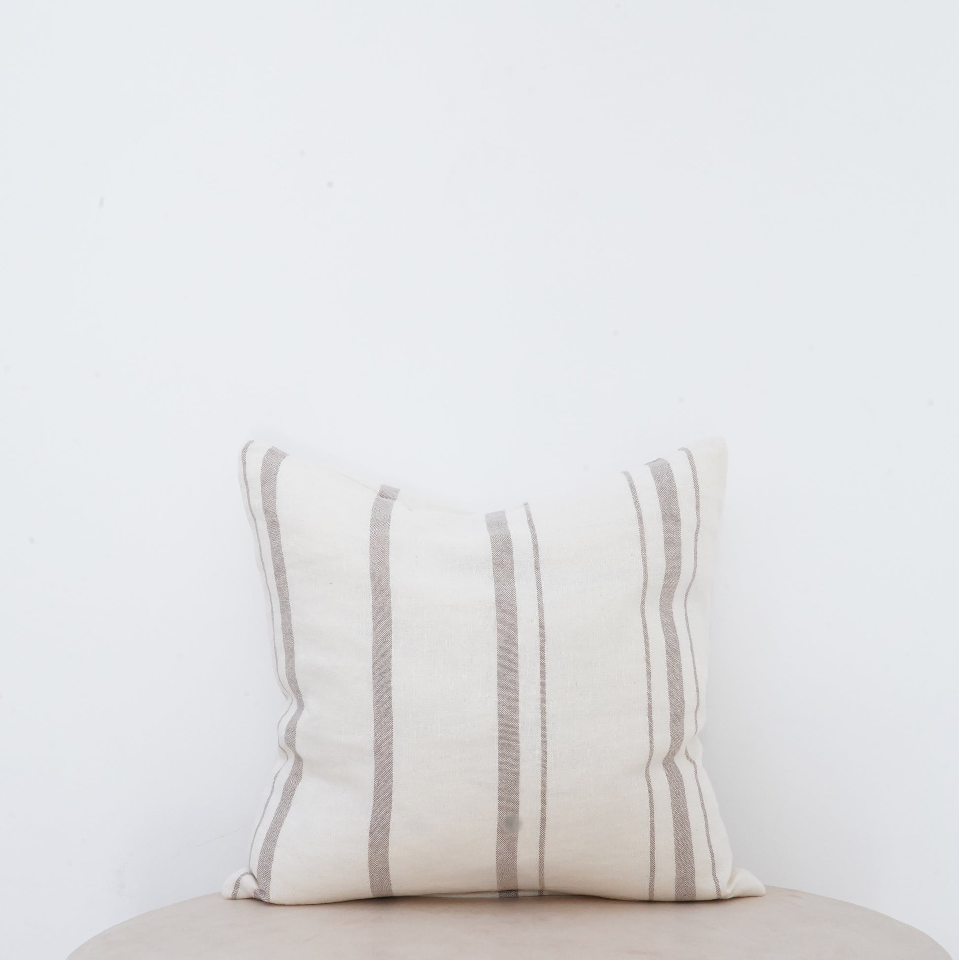 Fawn linen cushion with soft texture and French seam detailing.