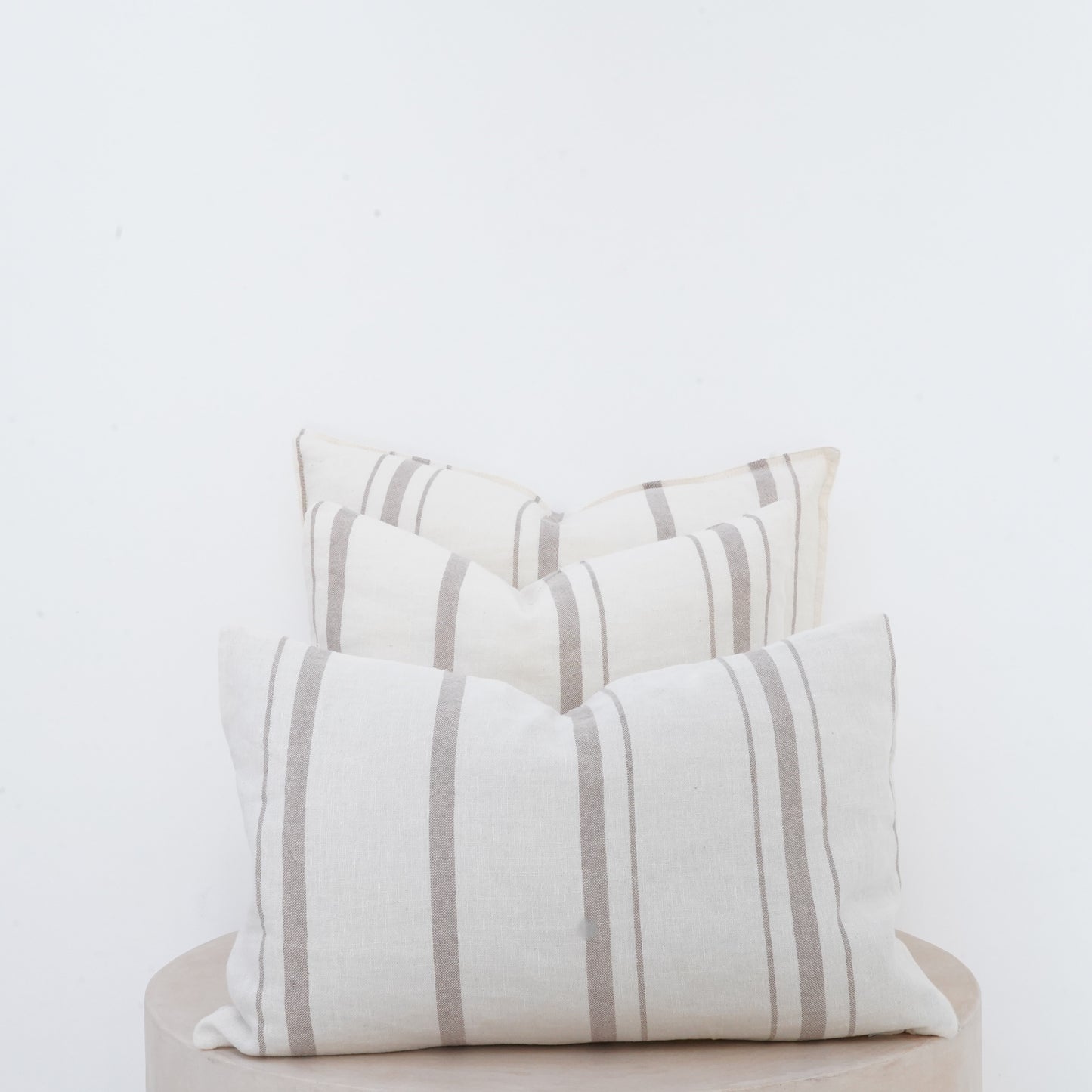 Fawn linen cushion with soft texture and French seam detailing.