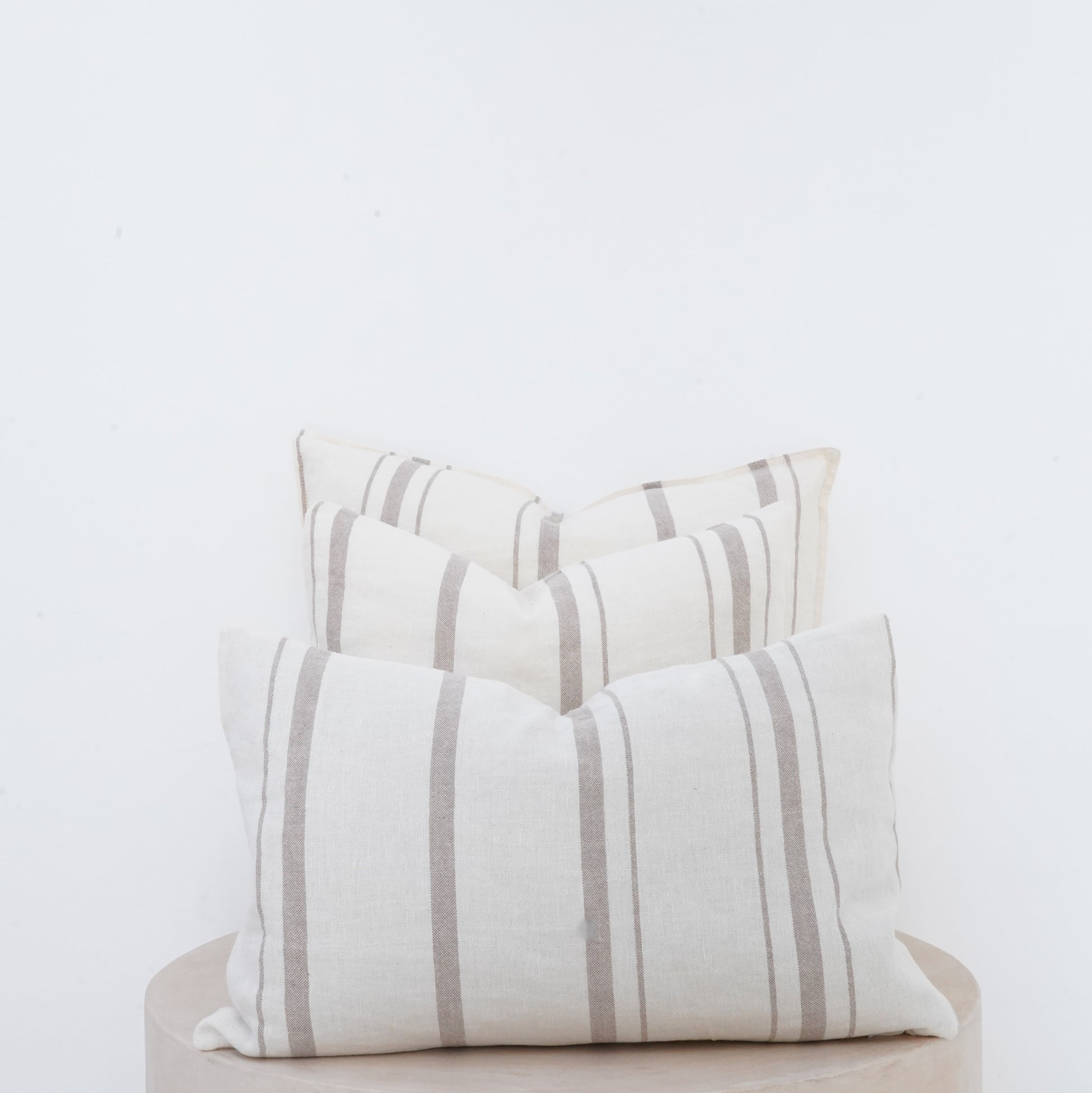 Fawn linen cushion with soft texture and French seam detailing.