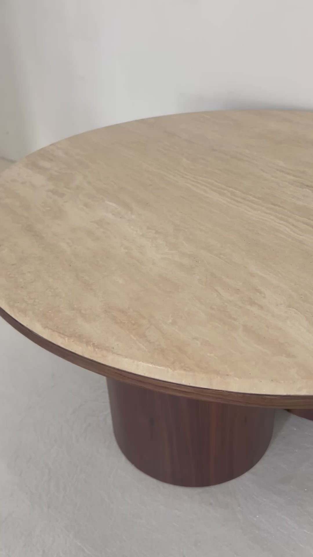 Round travertine coffee table with wooden legs, inspired by desert contours, styled in a contemporary living room.