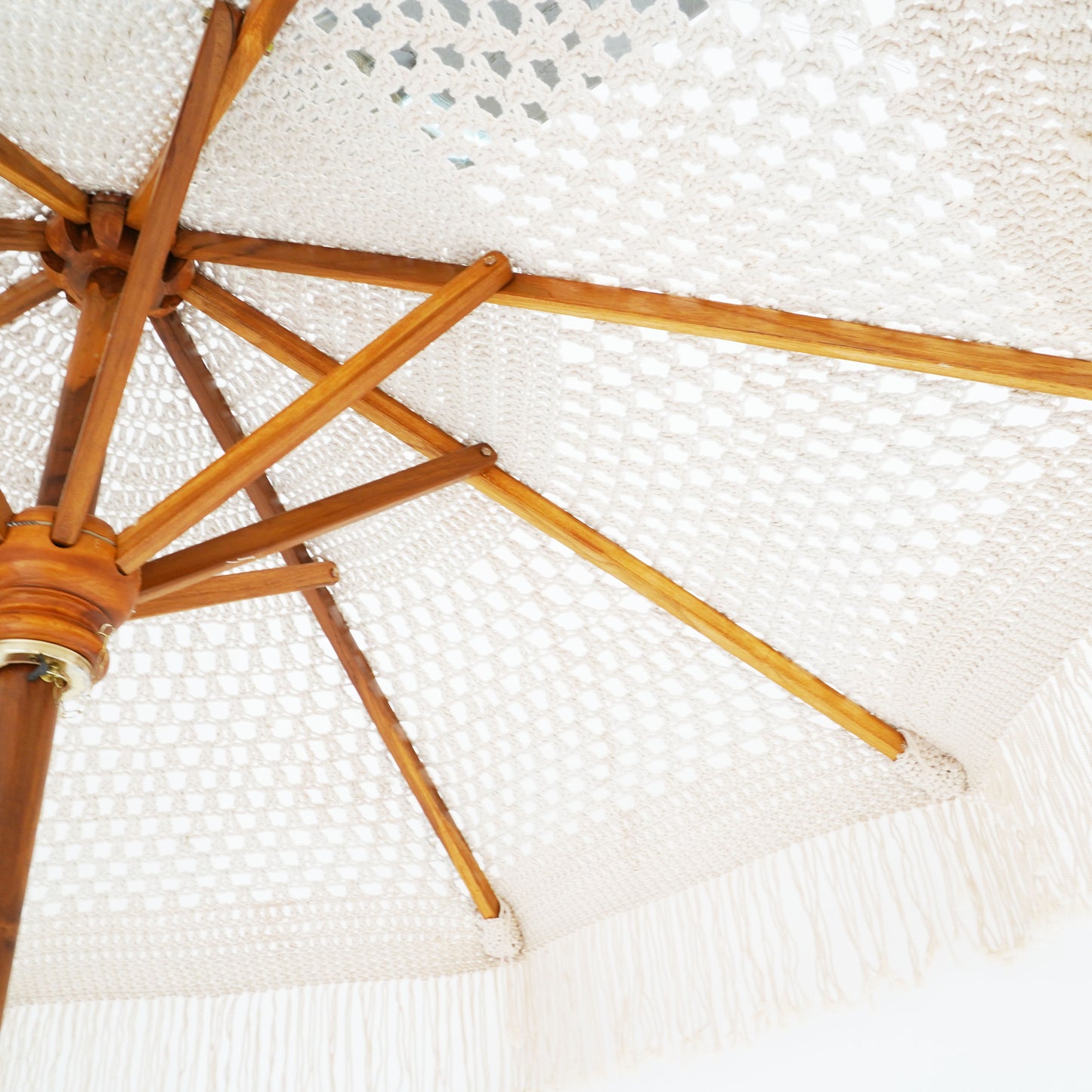 Handmade macrame umbrella with cotton rope canopy and sturdy stand, ideal for creating a boho beach vibe.